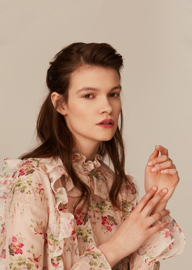 A woman wearing a frilly shirt with flowers
